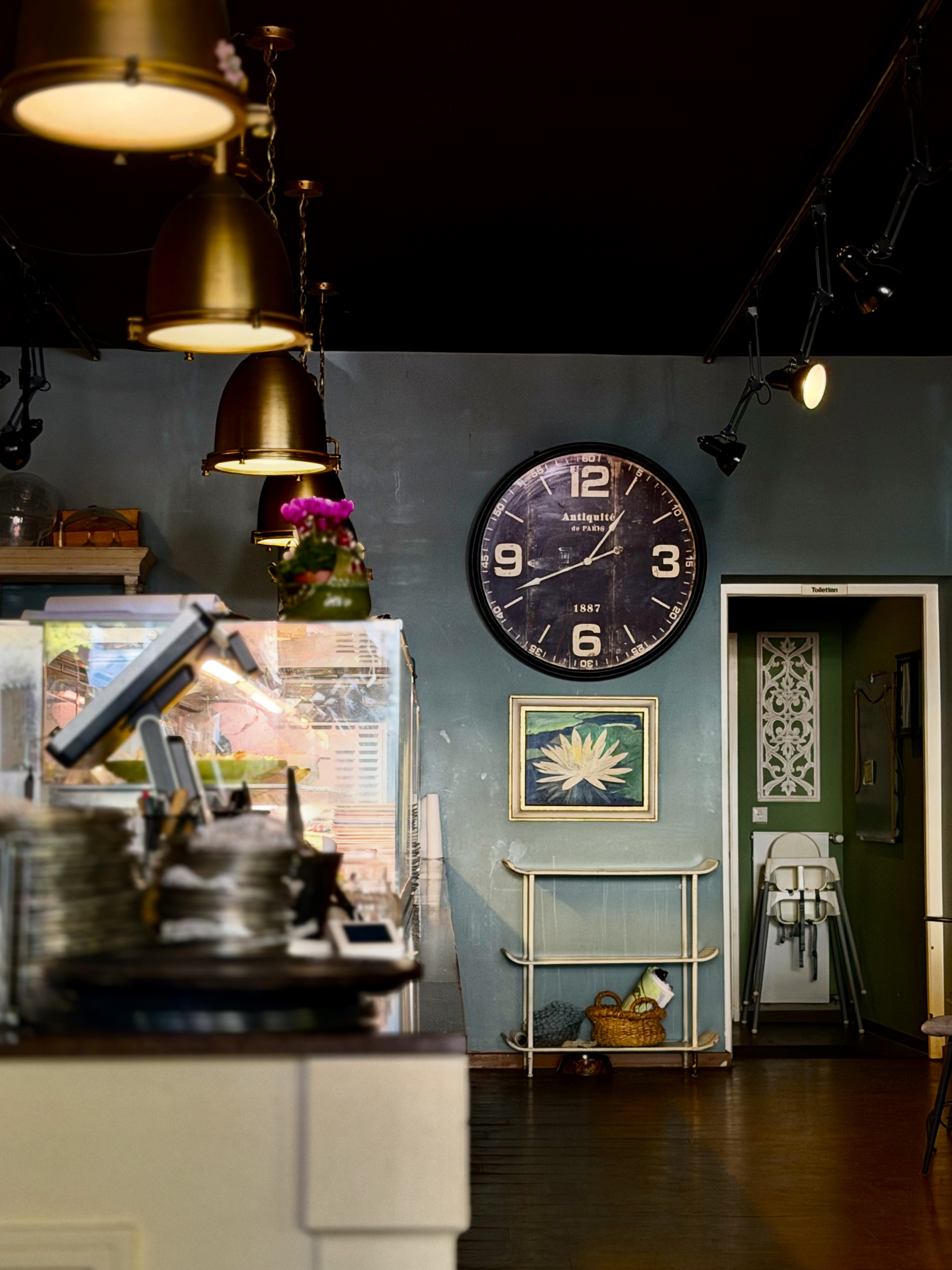 Café-Innenraum mit warmen Hängelampen und Vintage-Uhr